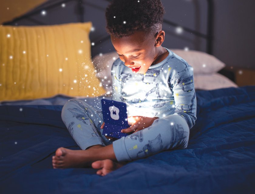 Young boy in blue pajamas smiling at a glowing Tooth Fairy box with magical sparkles
