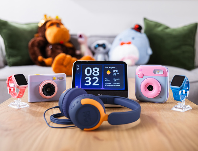 Colorful myFirst children’s technology products displayed on a wooden table, including smartwatches, instant cameras, headphones and a smart display designed for safe, creative digital experiences.